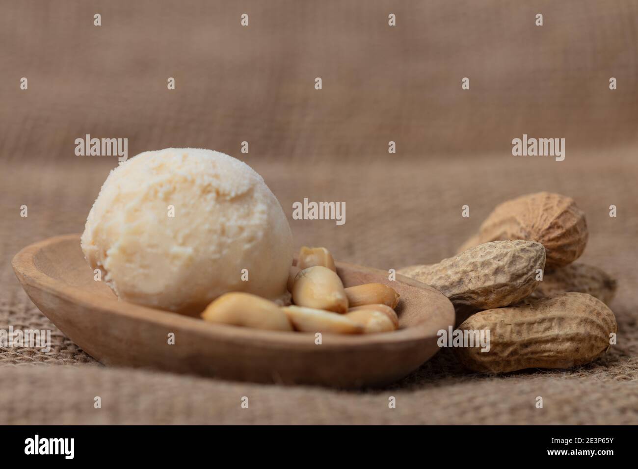 Fresh scoop of peanut butter ice cream with peanuts in wooden bowls Stock Photo