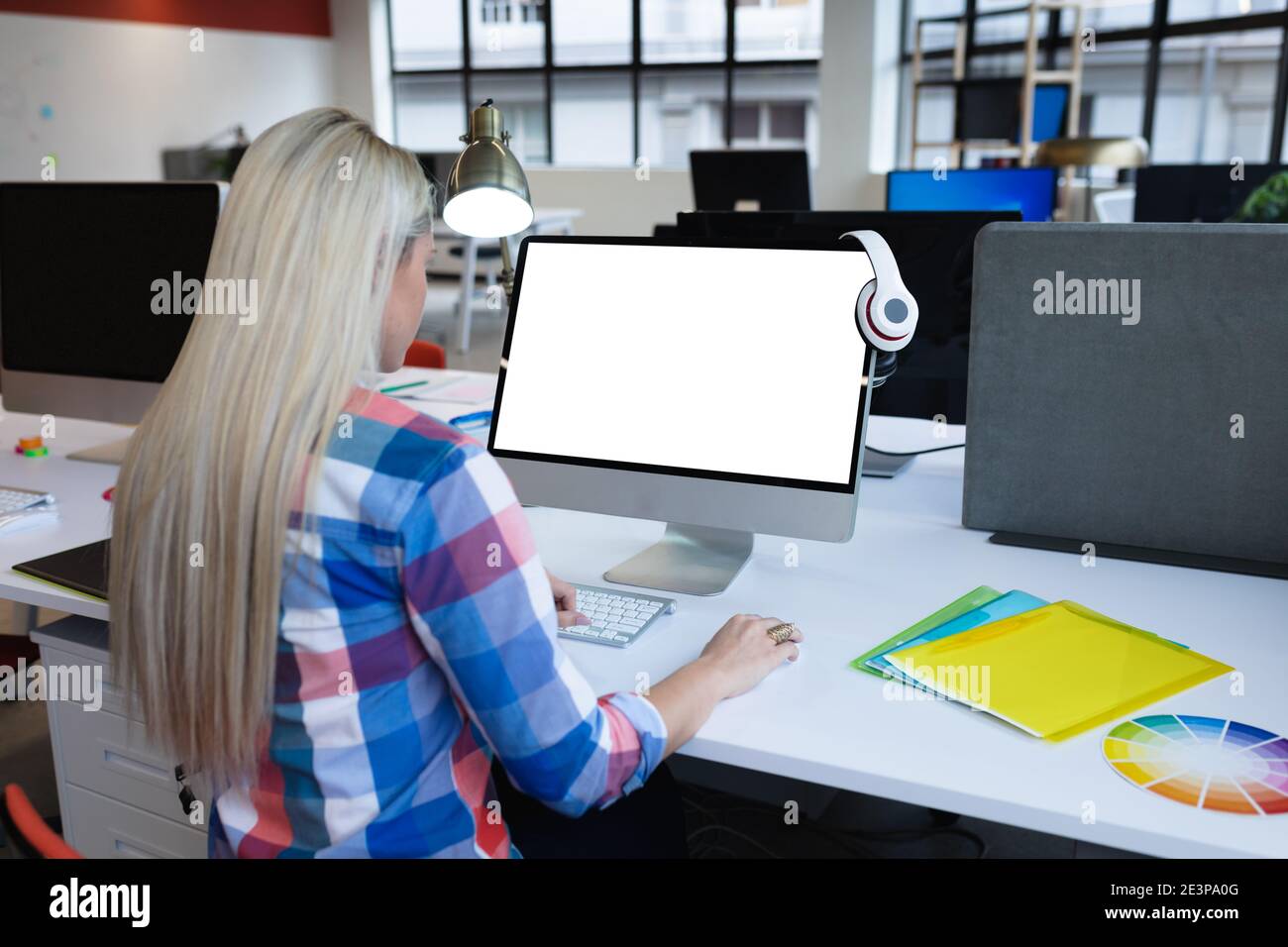 Caucasian businesswoman sitting at desk in creative office using desktop computer Stock Photo