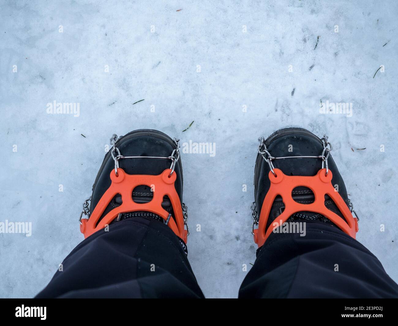 Two legs in winter boot with ice snow grips. Snow traction cleats