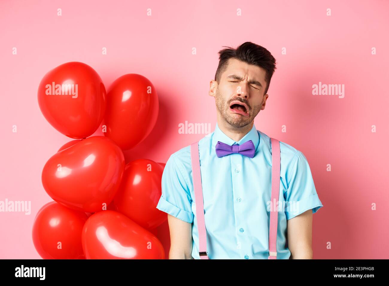 Valentines concept. Sad and heartbroken man crying over break-up, being cheated on lovers day, sobbing and feeling lonely, standing on pink background Stock Photo