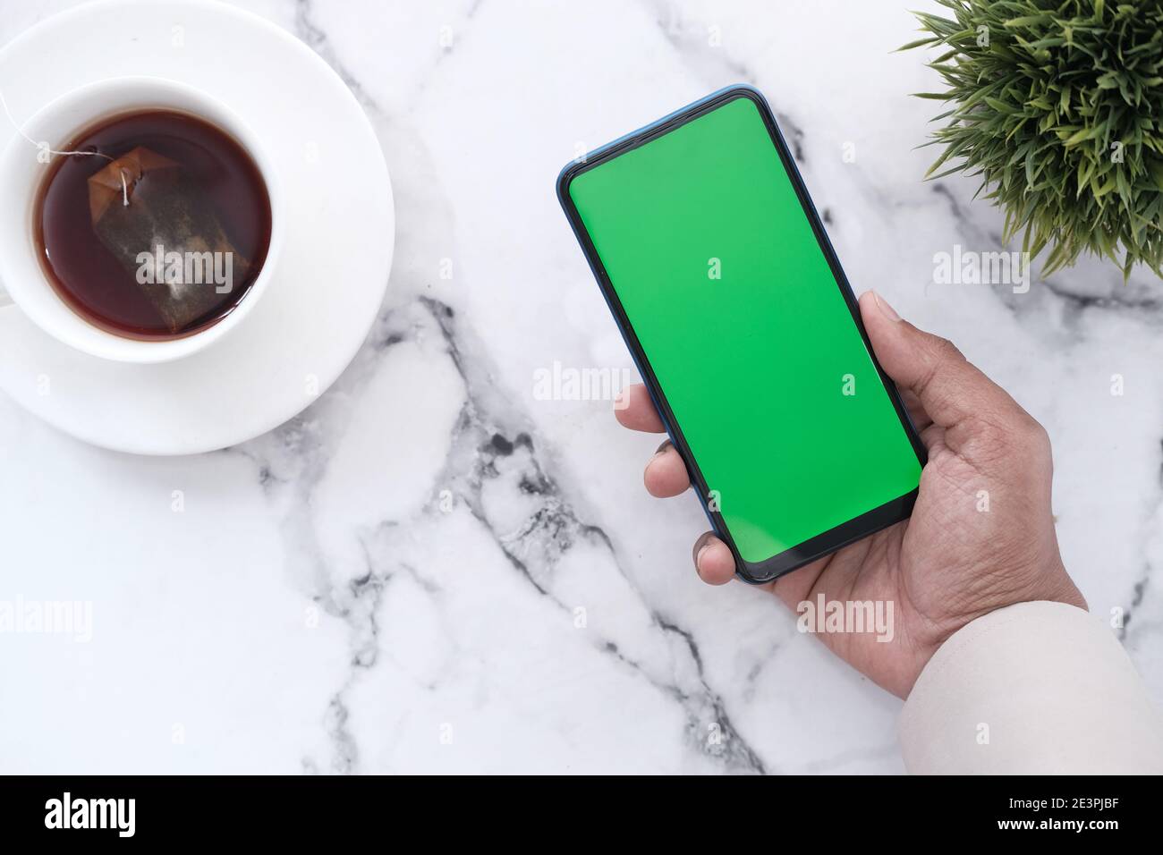 hand holding smart phone with empty screen on tile backgorund Stock Photo