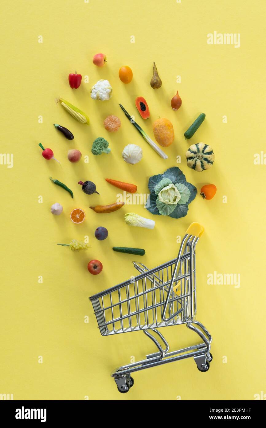 Grocery shopping concept - different foods with shopping tray on yellow background Stock Photo