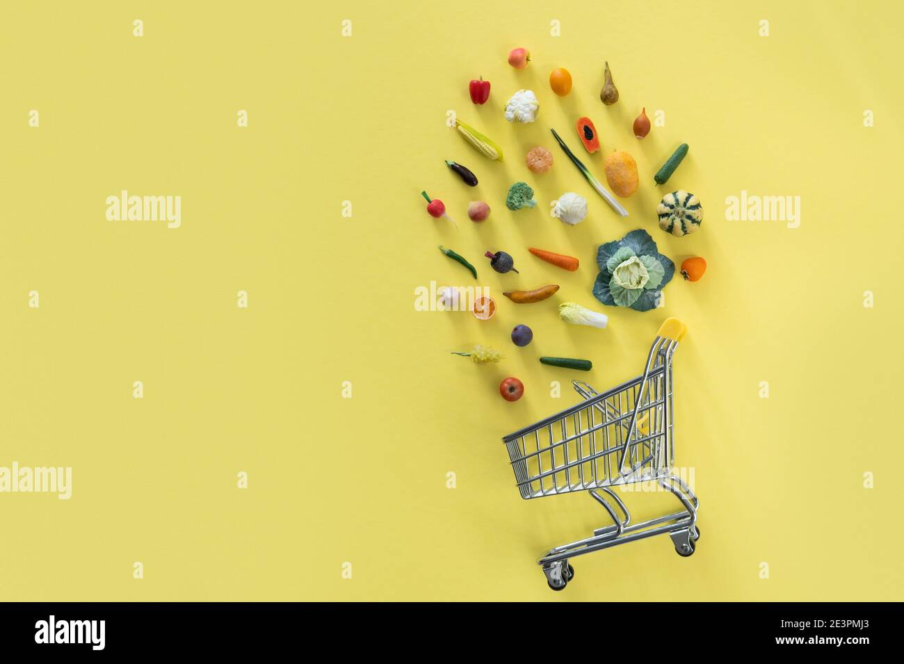 Grocery shopping concept - different foods with shopping tray on yellow background Stock Photo