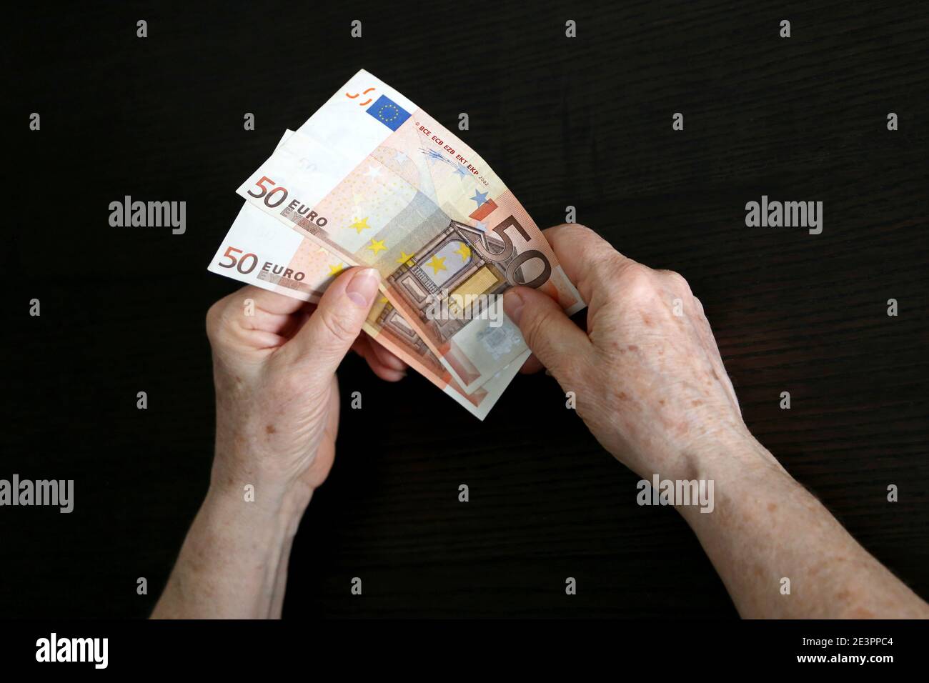 Elderly woman with euro notes in wrinkled hands. Concept of pension payments, savings at retirement, assistance to pensioners Stock Photo