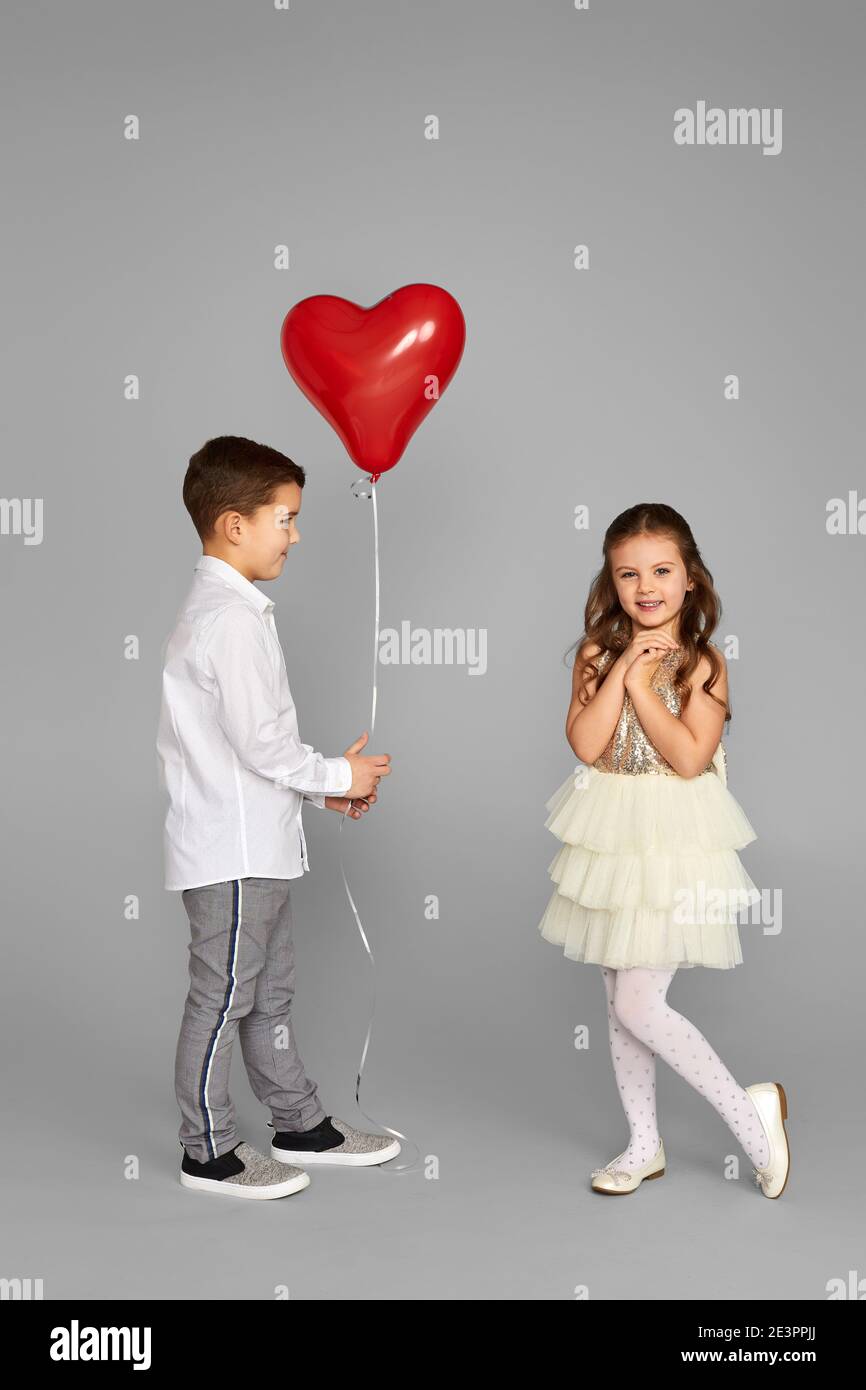 Waarnemen Jaar jogger couple of little girl and boy with red heart balloons isolated on gray  background. boy gives shy girl balloon. St. Valentine's Day Stock Photo -  Alamy