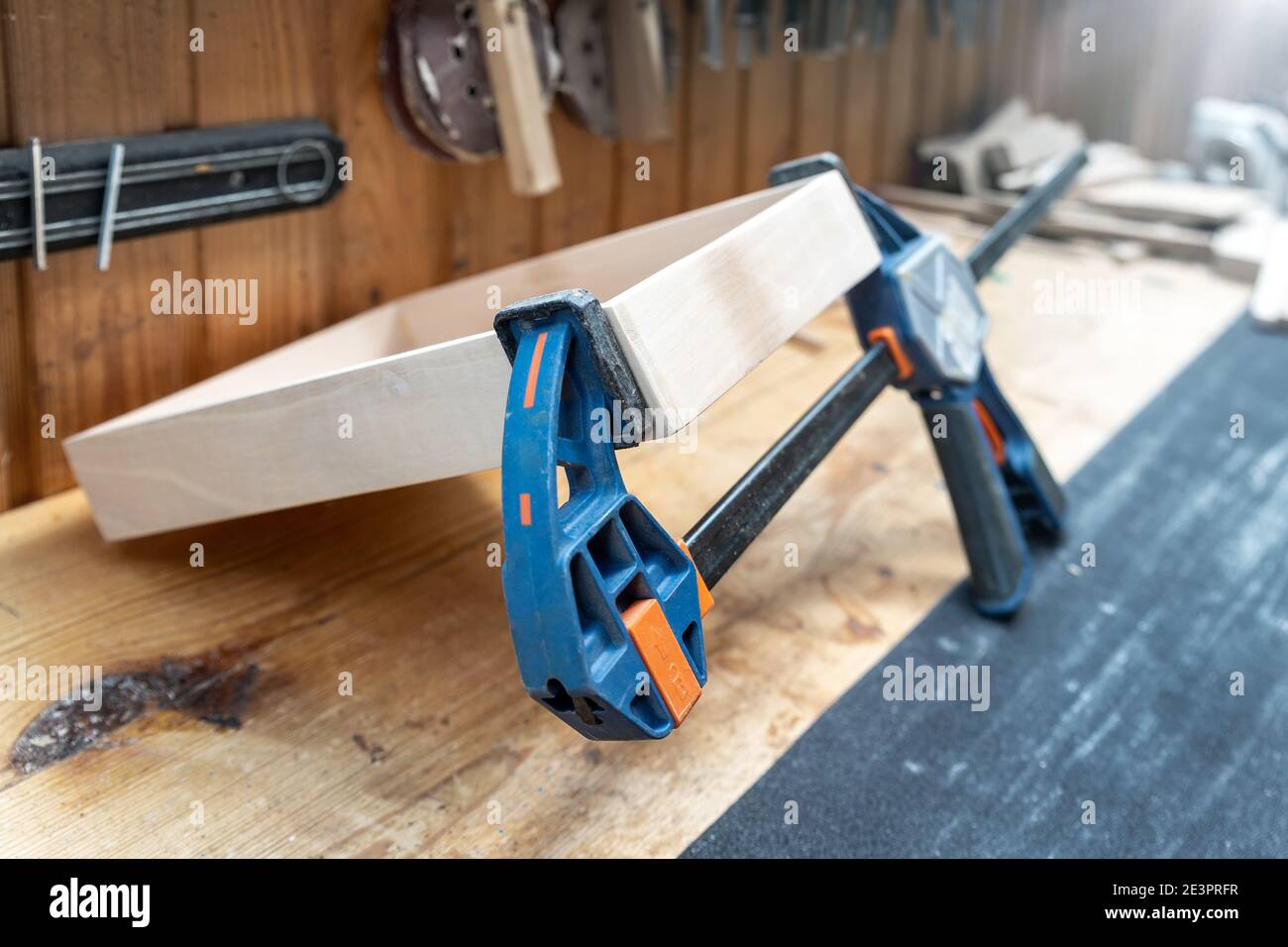 Joining wooden handmade box with clamps joiners after glueing. Different chisels, drills and pencils at craftsman workshop. DIY instruments on wood Stock Photo