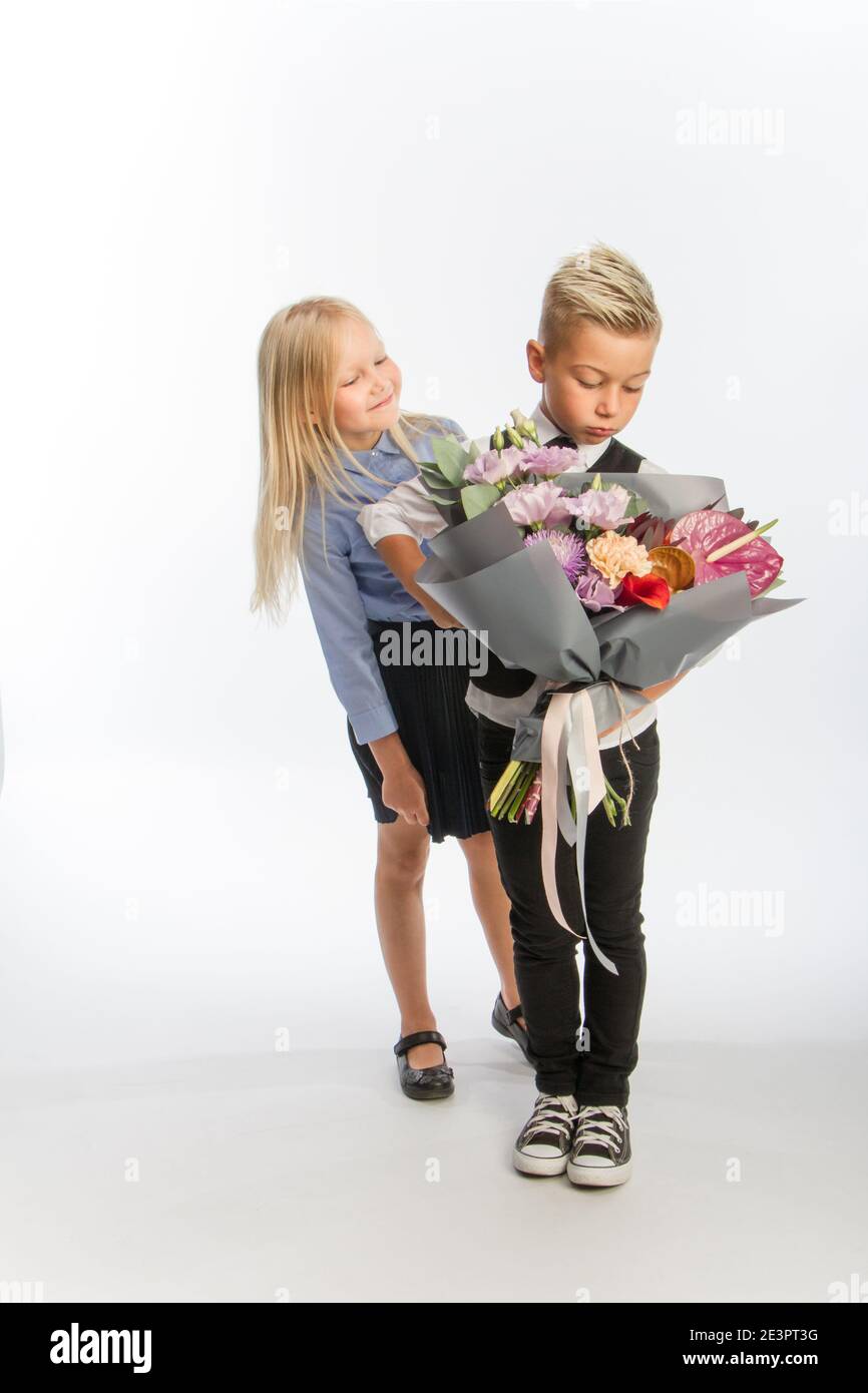 Studio portrait boy gives girl festive bouquet, congratulatory concept, white background, copy space Stock Photo