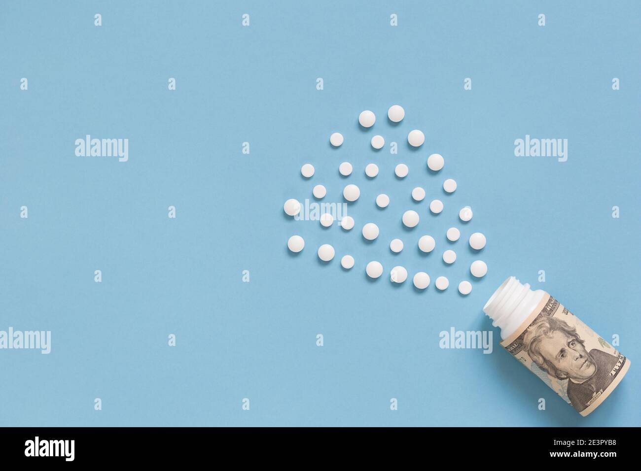 Medical bottle with dollars and many white pills. The concept of insurance medicine, high cost of drugs. Isolated on a blue background. Healthcare. Stock Photo