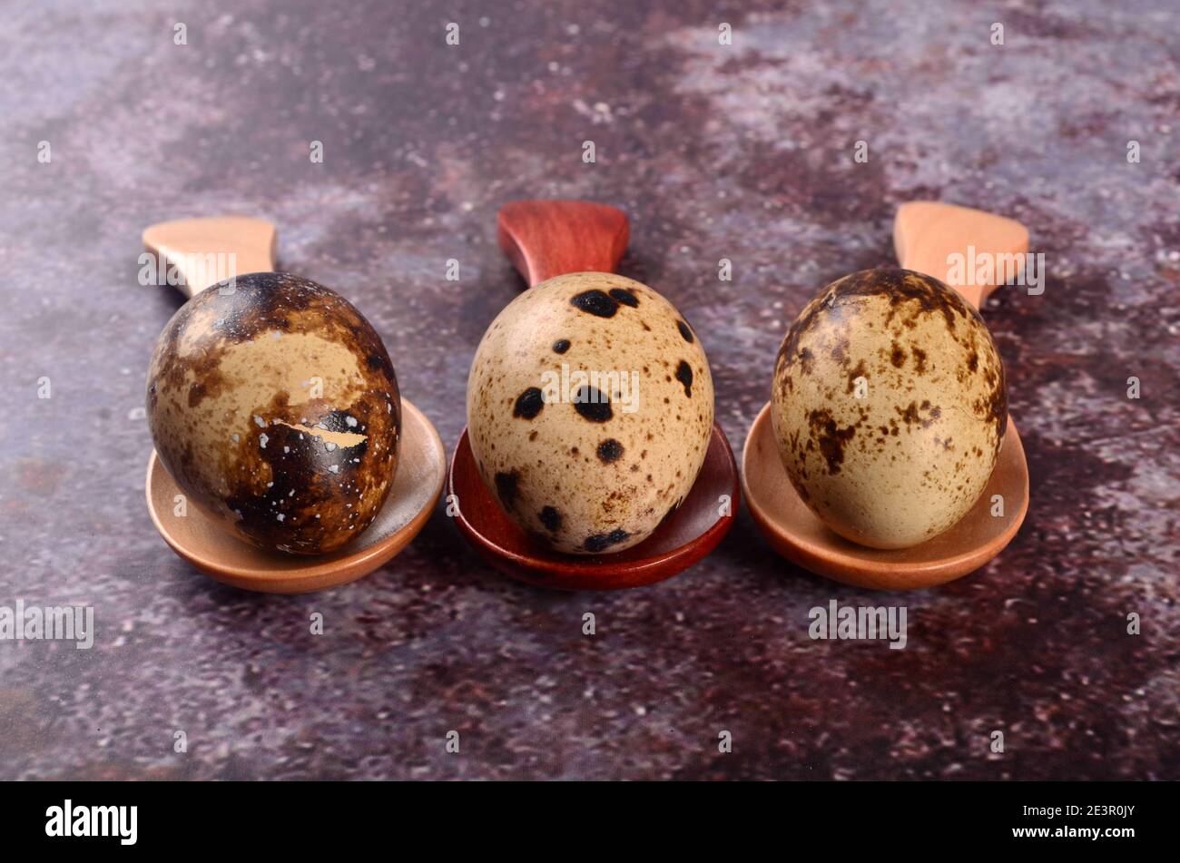 Three quail eggs in small wooden spoons, gray background Stock Photo ...