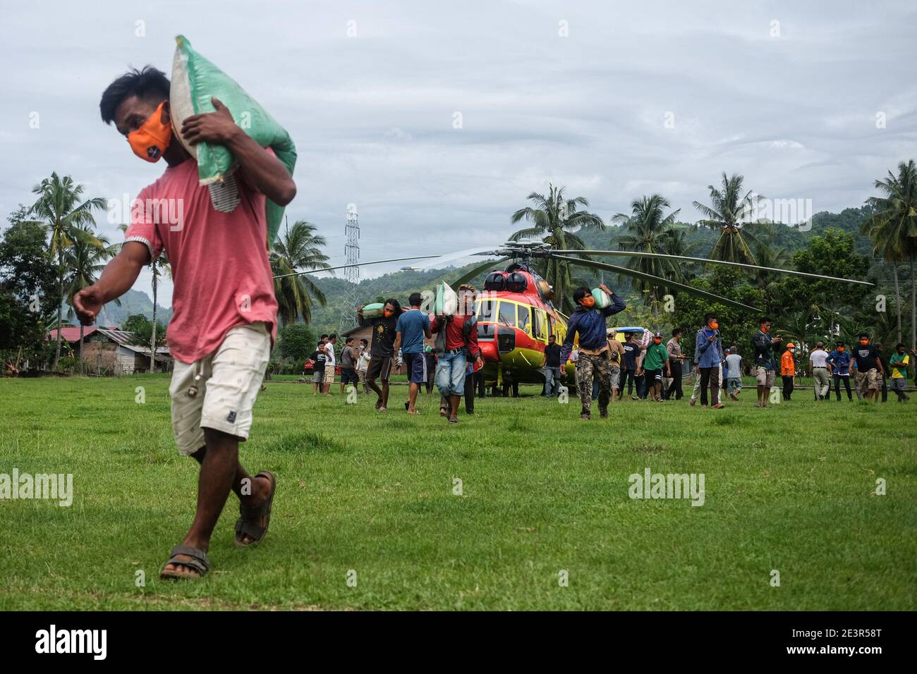 (210120) -- WEST SULAWESI, Jan. 20, 2021 (Xinhua) -- People bring daily necessities dropped by a National Disaster Management Agency helicopter for isolated village after a 6.2-magnitude earthquake hit Majene, West Sulawesi, Indonesia, Jan. 20, 2021. (Photo by Niaz Sharief/Xinhua) Stock Photo