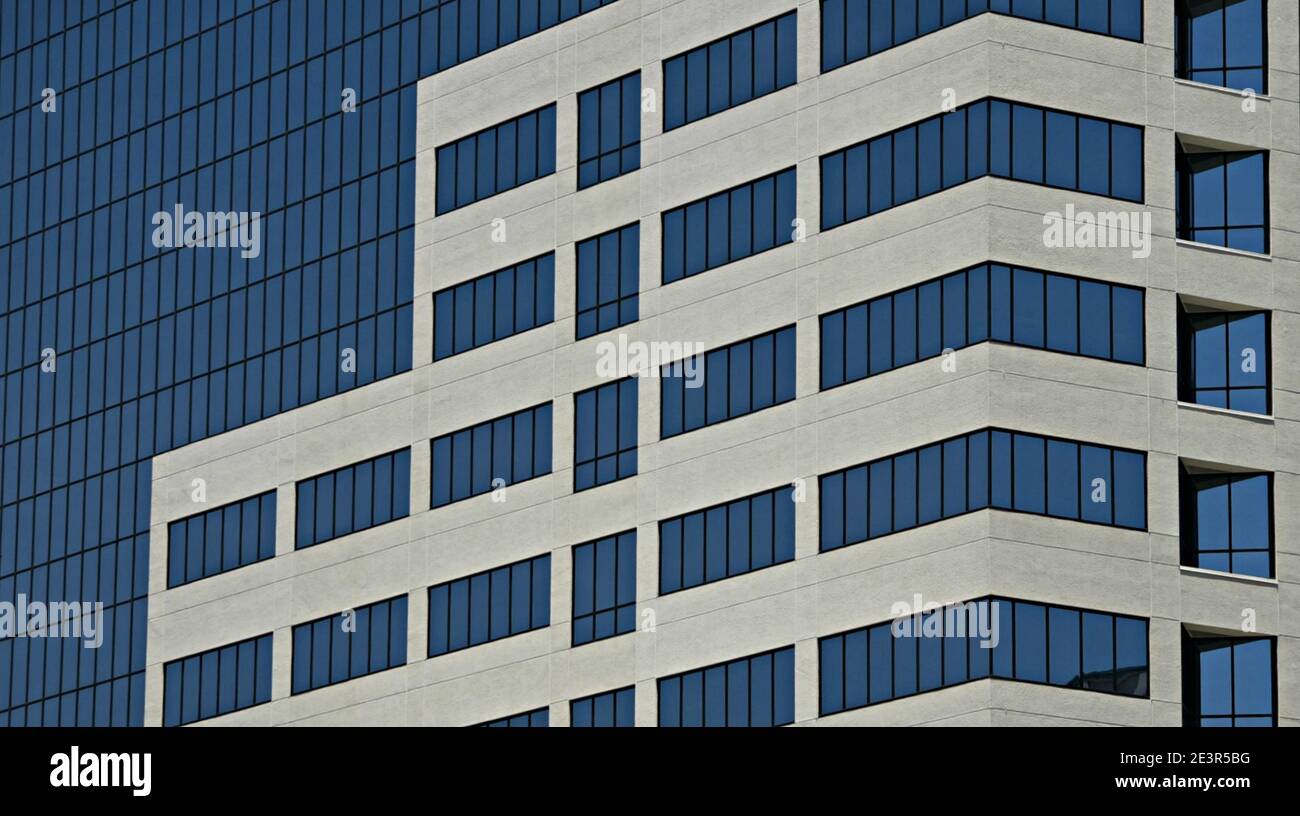 Modern urban skyscraper facade with symmetrical blue glass windows and ...