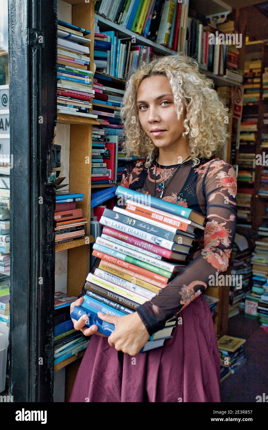 GREAT BRITAN / London / Woman holding a stack of books in front of second hand bookshop. Stock Photo