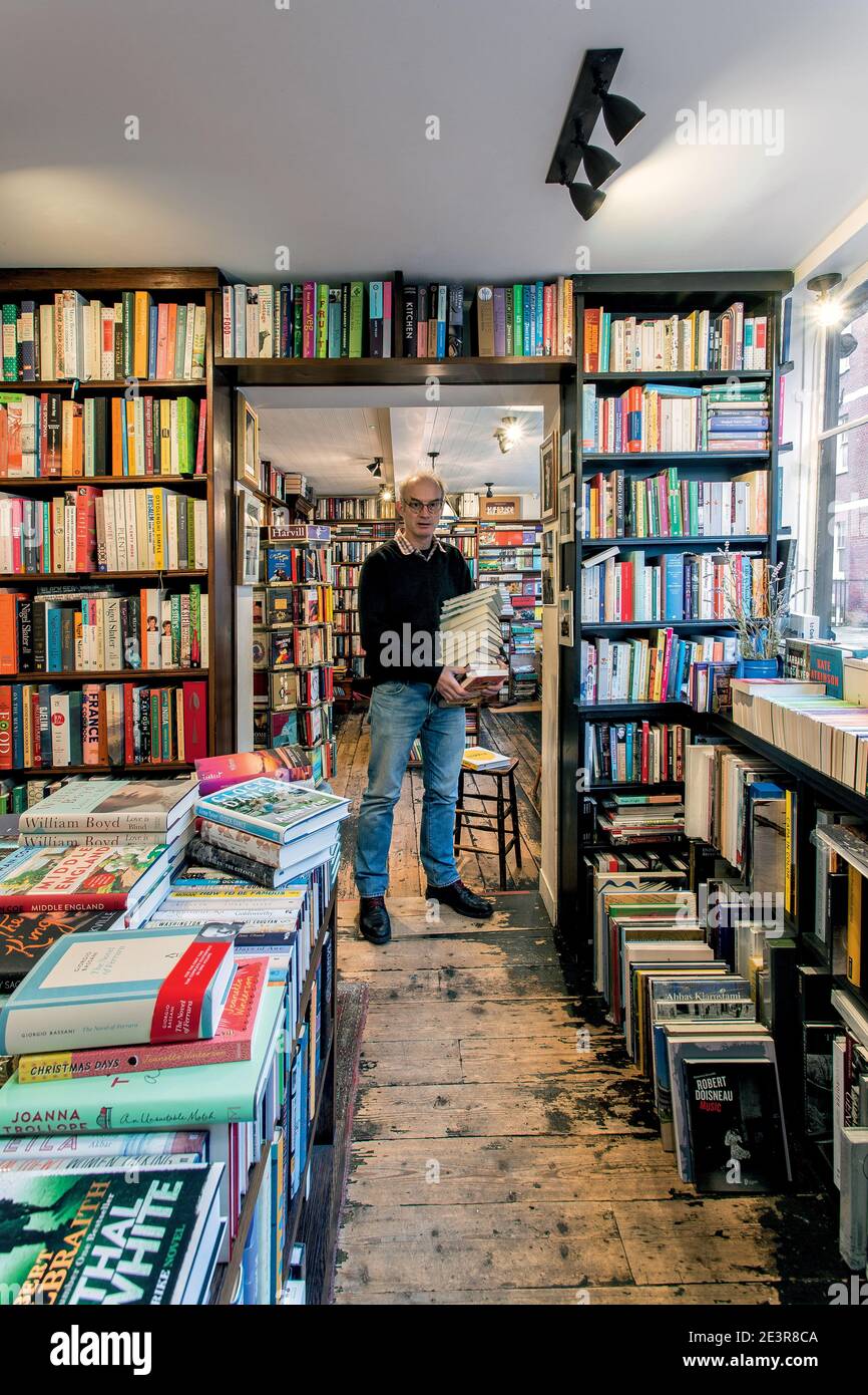 GREAT BRITAN / London /Bookstores /The proprietor Johnny de Falbe of John Sandoe Books in London. Bookseller holding stack of books. Stock Photo