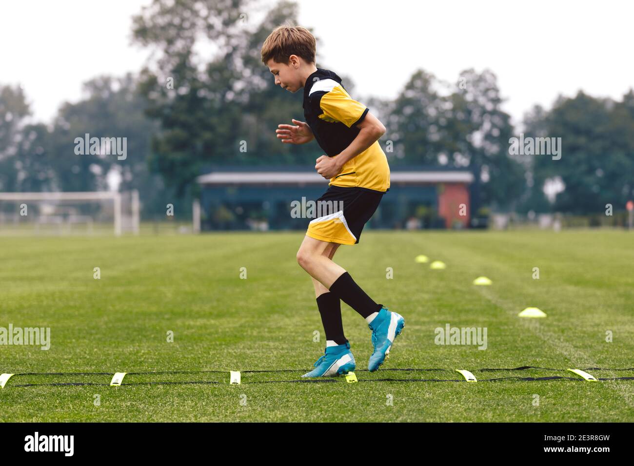 Junior football club player training on soccer ladder. Football training for sport team. Young boy running on agility ladder. Football training Stock Photo