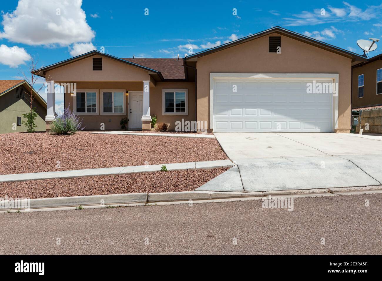 The facade of a suburban house with garage and driveway, in a suburb in the outskirts of the city of Gallup, New Mexico, USA Stock Photo