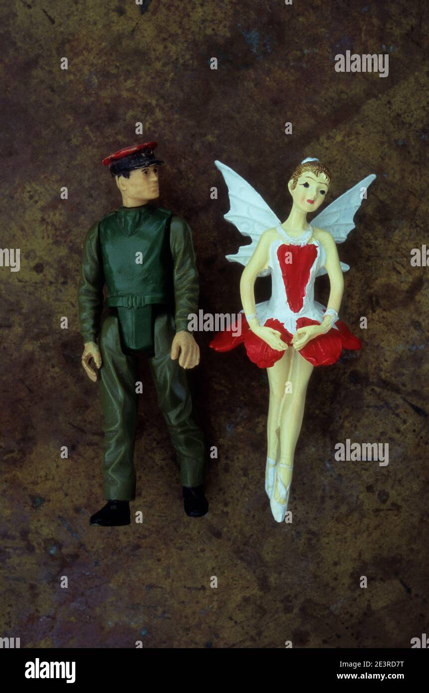 Plastic models of soldier or security pr action man looking at girl ballerina dressed as fairy Stock Photo