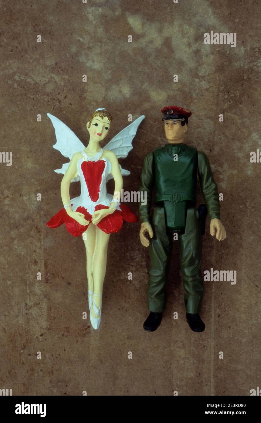 Plastic models of soldier or security pr action man looking at girl ballerina dressed as fairy Stock Photo