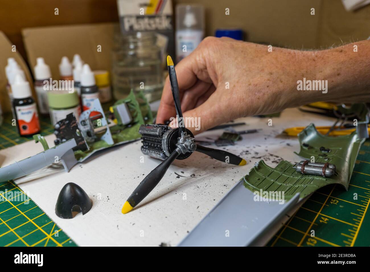Man constructing engine of Airfix Spitfire model aeroplane 1/24th in scale on home desk Stock Photo