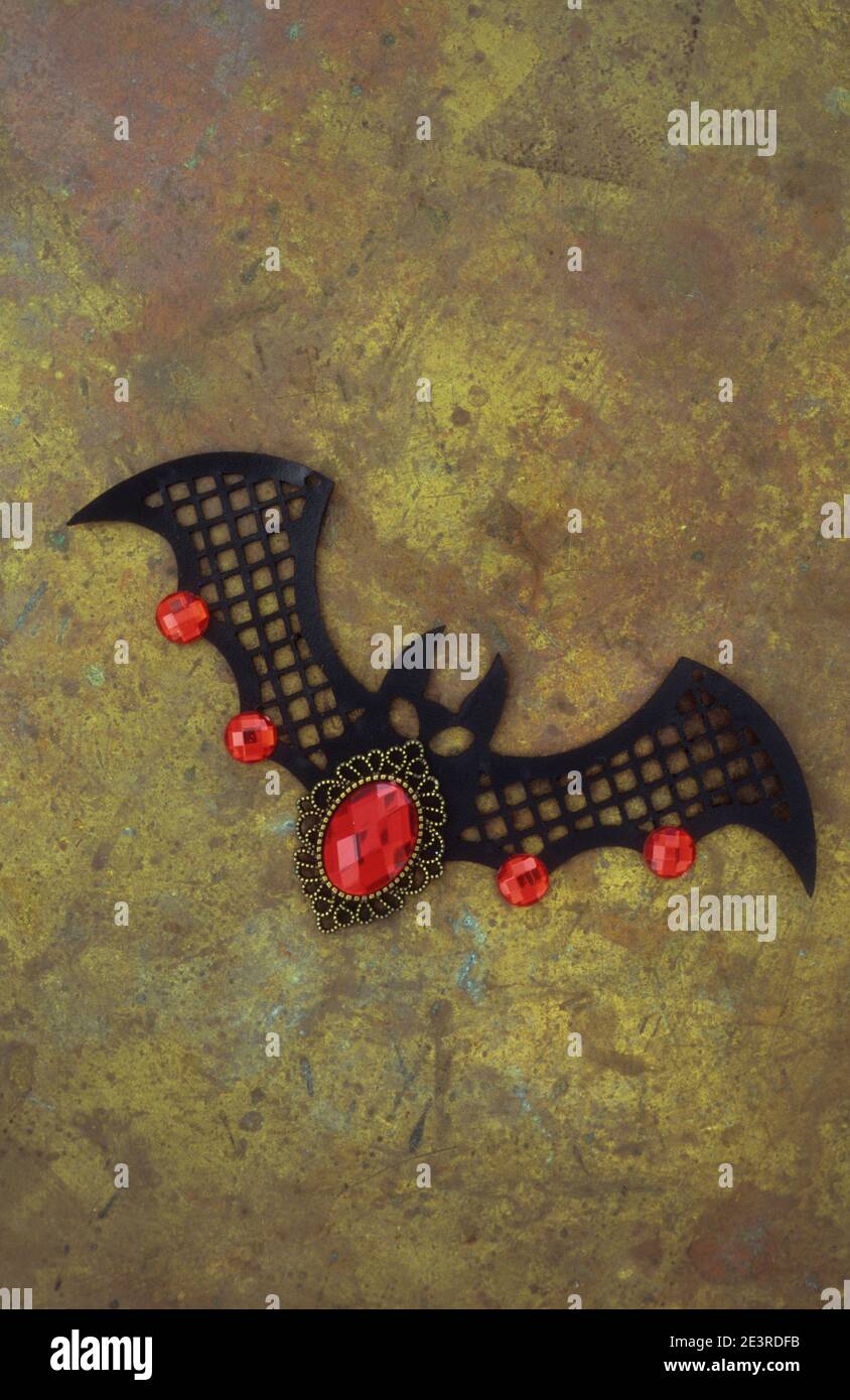 Black plastic cutout of bat  in flight with red jewels attached to body and wings Stock Photo