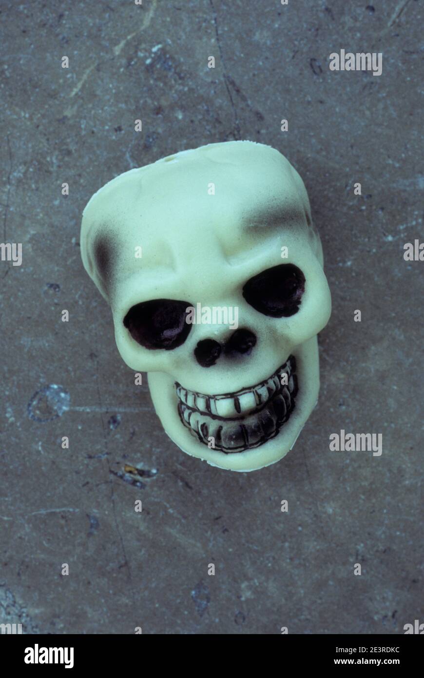 Face mask of grinning human skull lying on marble Stock Photo