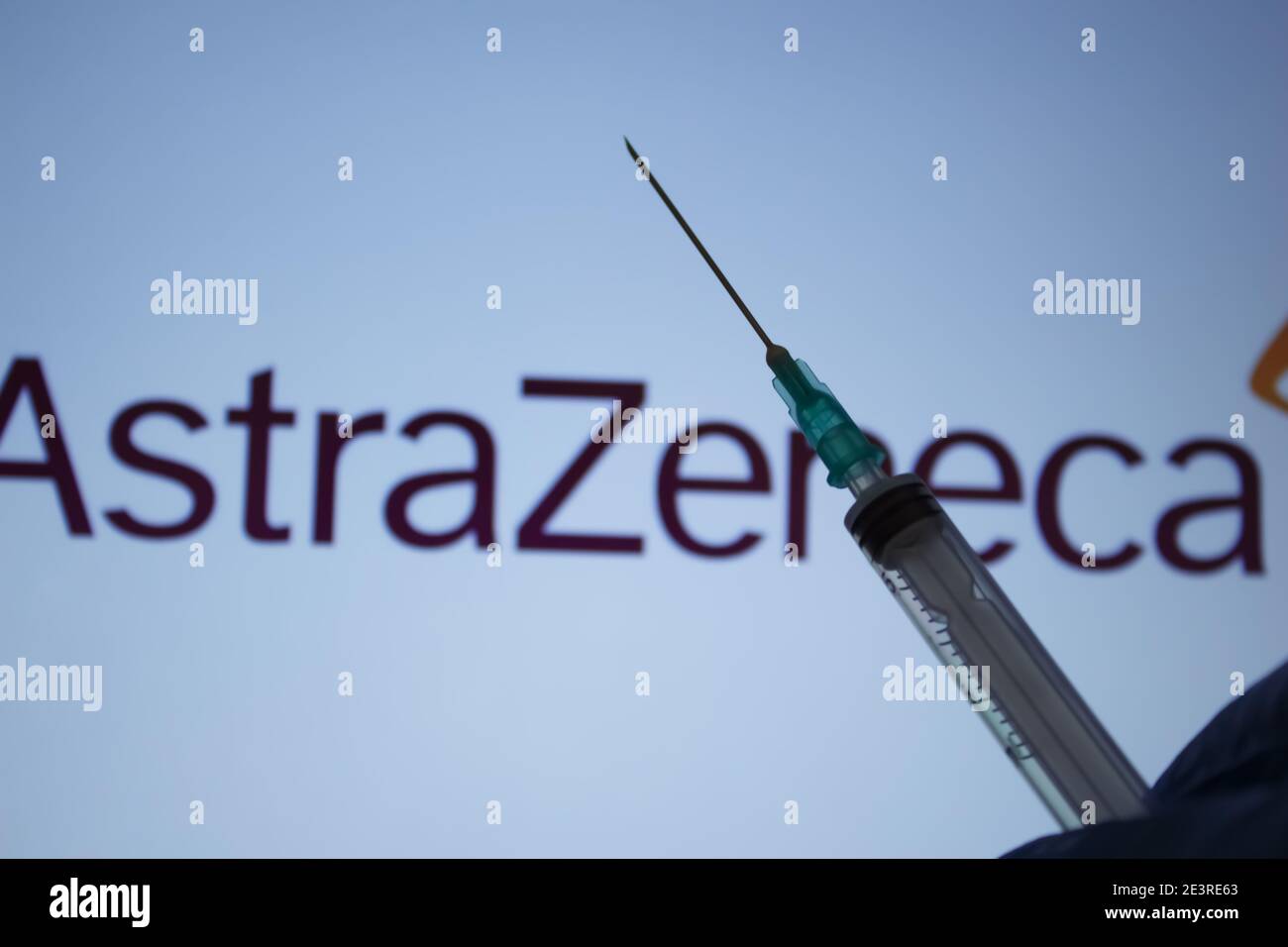 Covid-19 vaccine concept. Syringe needle, Blurred AstraZeneca company logo on the background. Coronavirus vaccination concept. Stock Photo