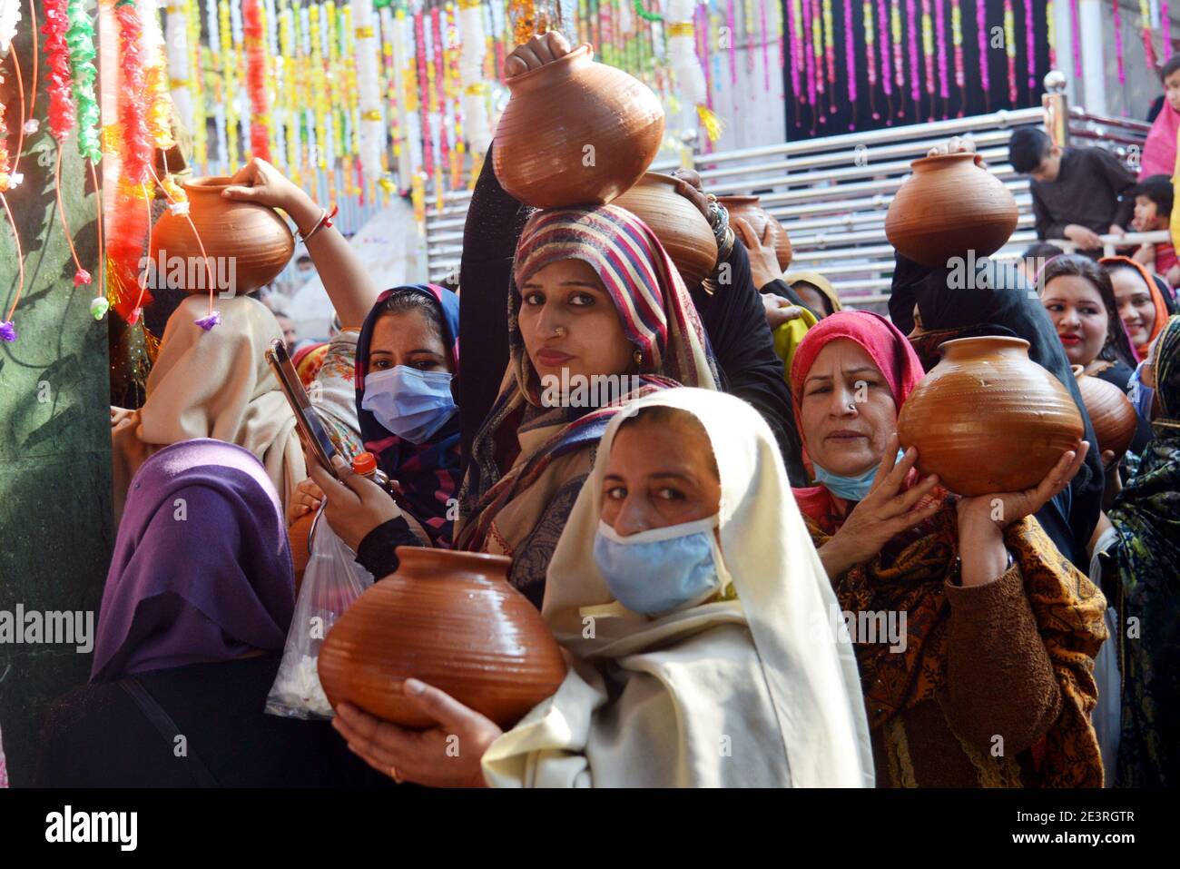 Pakistani women devotees bringing water for ablution of the graves at the shrine of the mausoleum of Ruqayyah Bint Ali known as Bibi Pak Daman Lahore Stock Photo