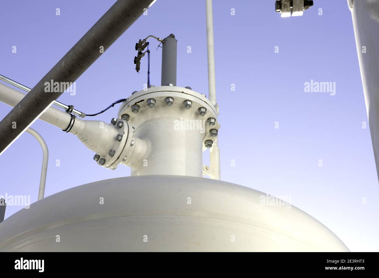 industrial background with pipes, joints, bolts and pressure tank color white with blue sky as background Stock Photo