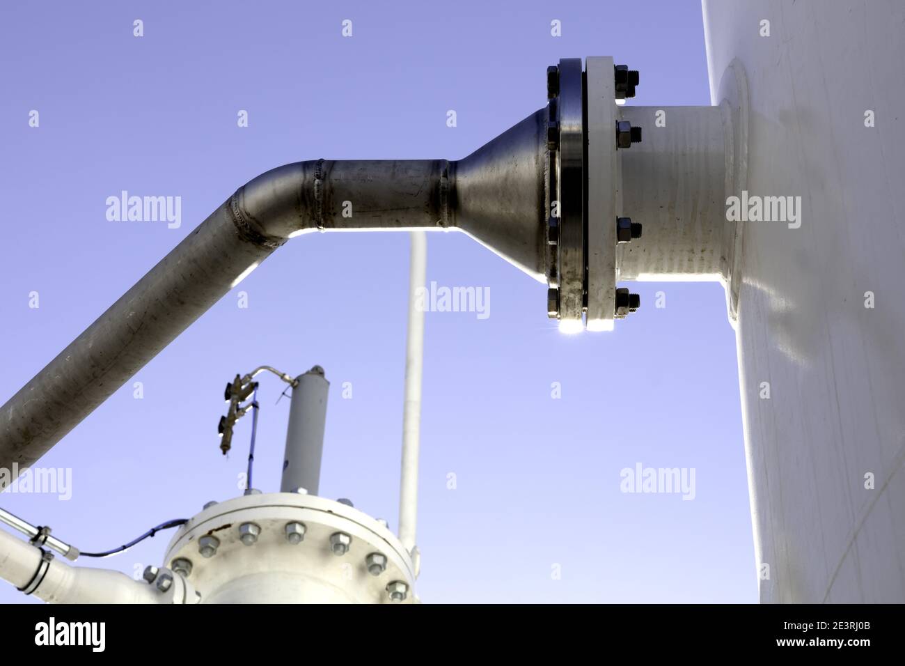 pressure joint with screws of a steel pipe to a white tank Stock Photo