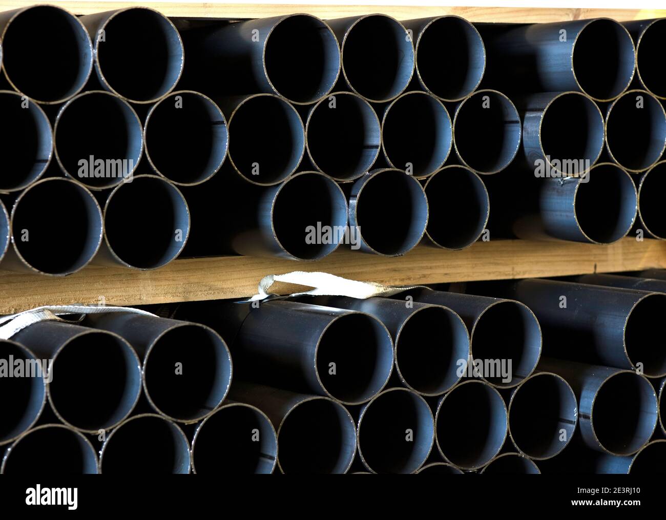 pipes of iron stacked in the warehouse on large wood pieces Stock Photo