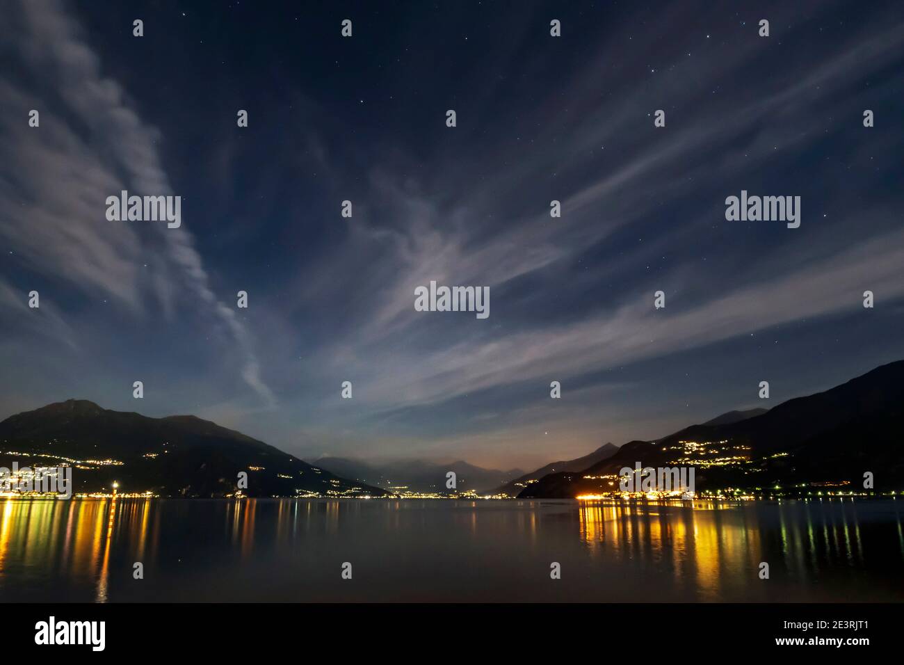 Spectacular night on Lake Como with the stars shining between a veil of clouds and the colored reflections on the water of the lights of the towns alo Stock Photo