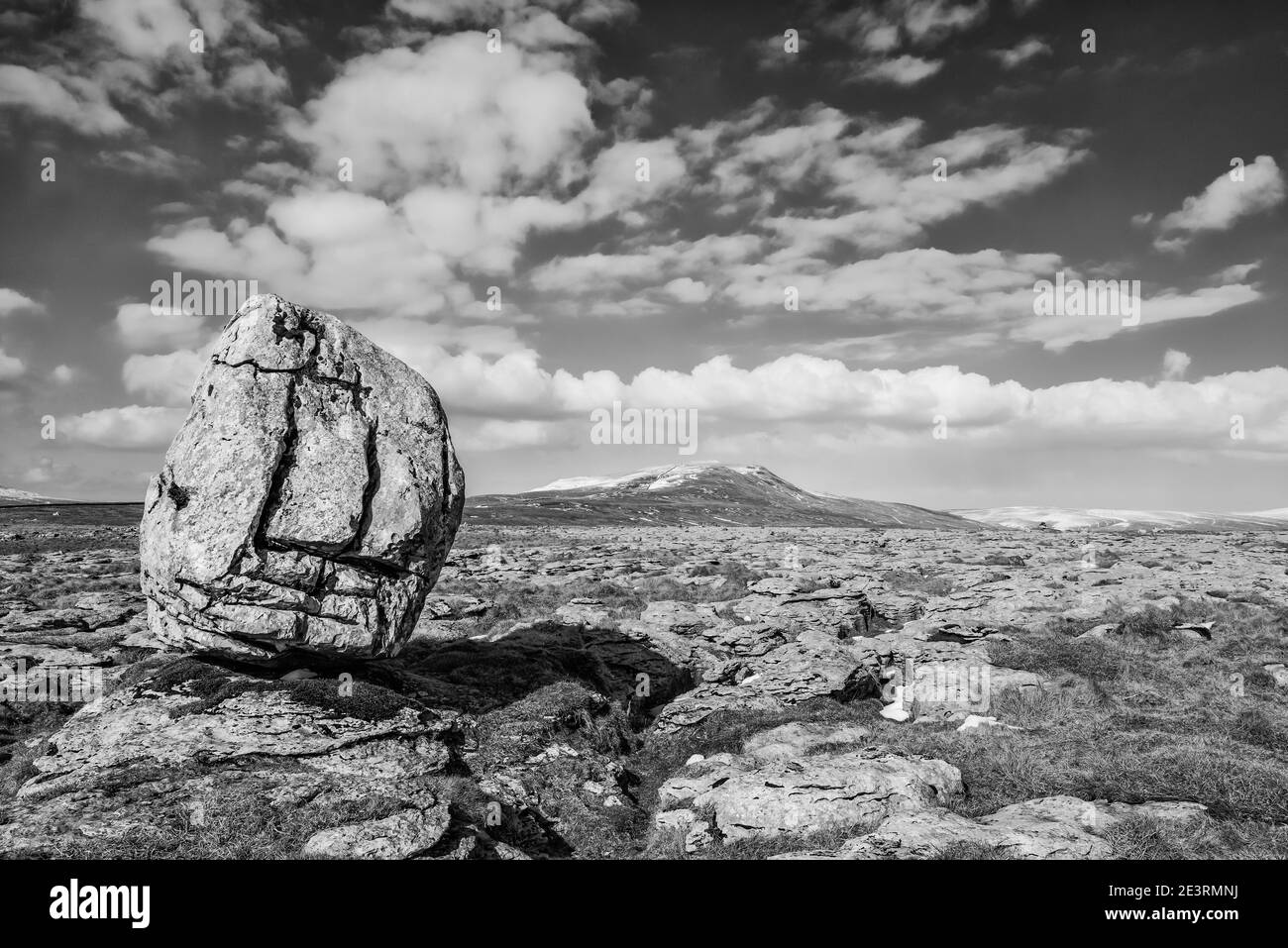 Fabulous winter scenery in monochrome of Whernside, the highest of the famous Yorkshire Dales Three Peaks; as seen from Twistleton Scales Moor with the largest of the limestone erratic boulders left over as a parting gift from the ice-age. Stock Photo