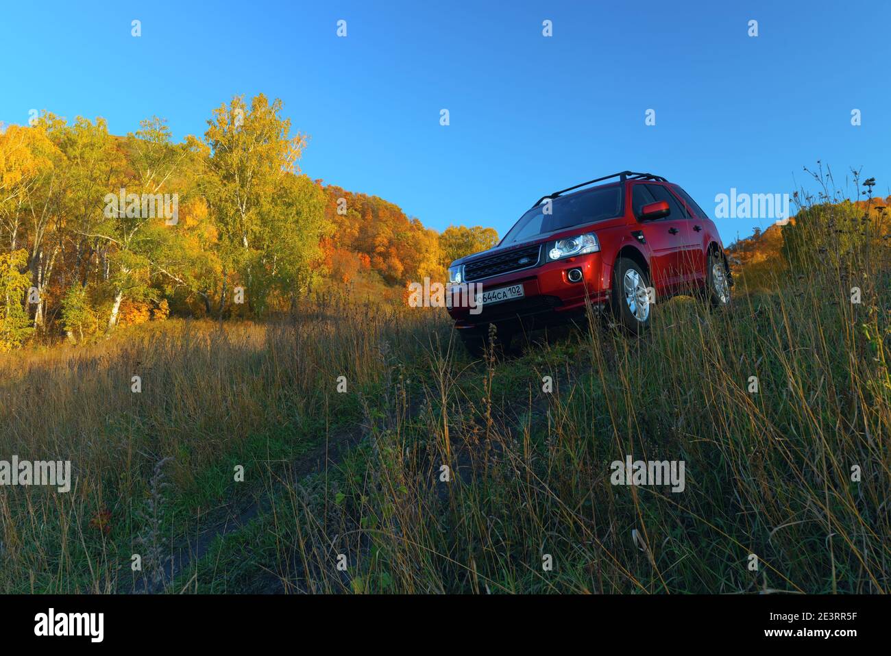 RUSSIA, Rep. of BASHKORTOSTAN, Kugarchinsky District, MRAKOVO village - SEPTEMBER 27, 2020. LAND ROVER FREELANDER 2 red SUV descending dirt road, autu Stock Photo