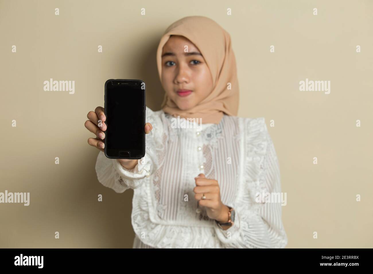 Happy Asian woman in hijab demonstrating mobile cell phone. Portrait of ...