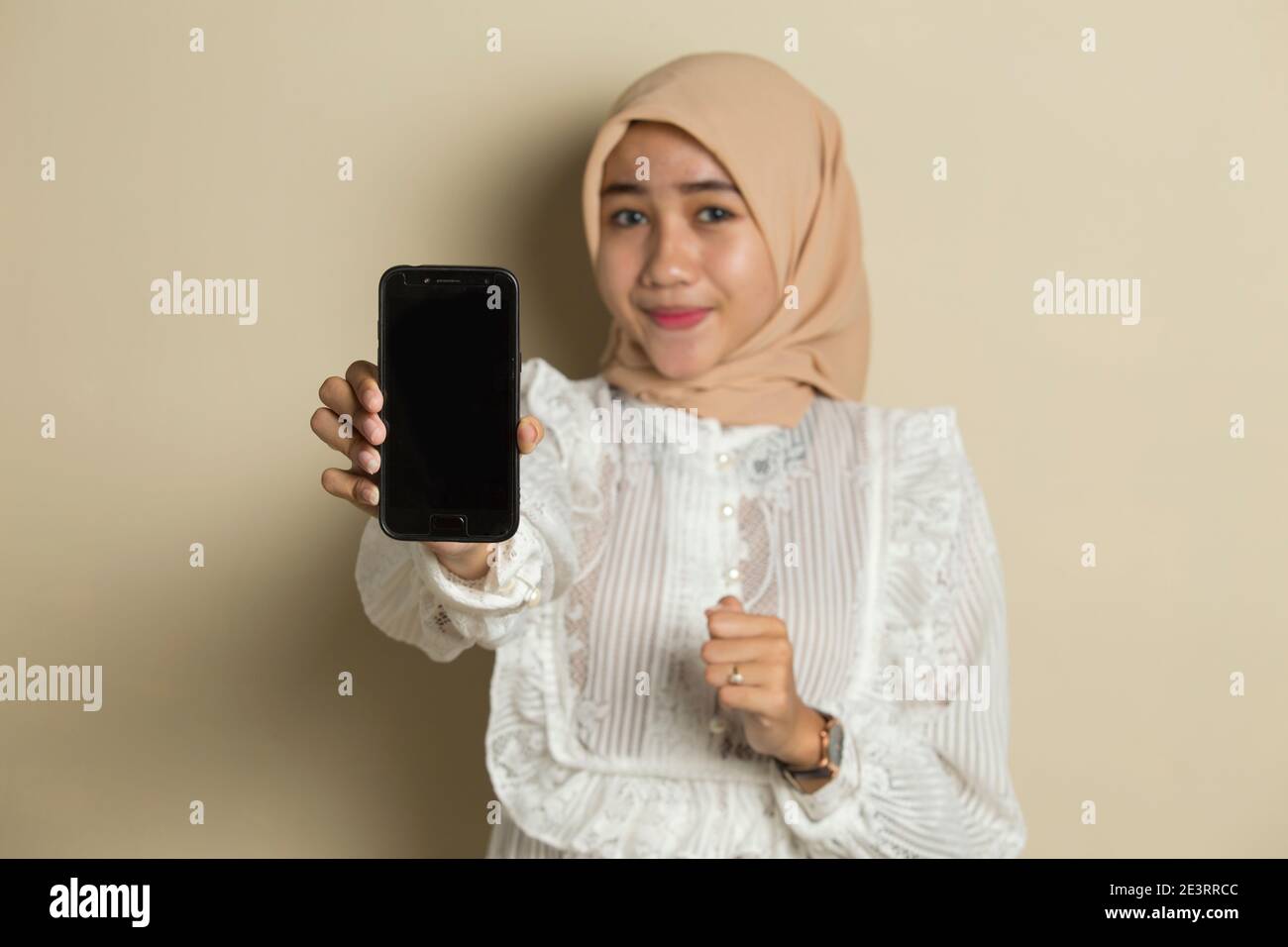 Happy Asian woman in hijab demonstrating mobile cell phone. Portrait of ...