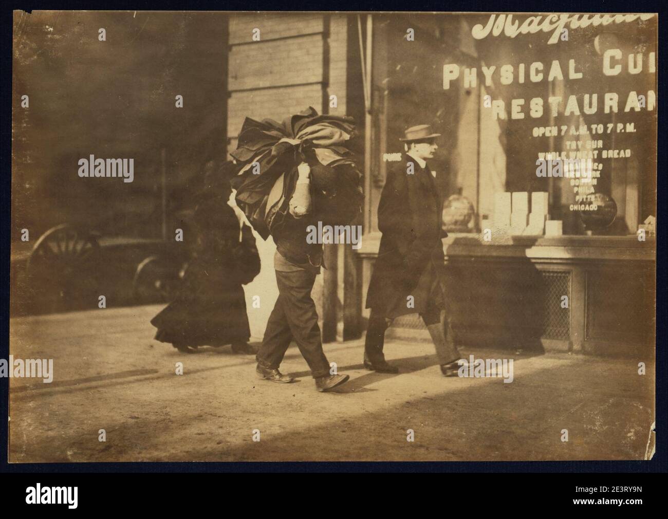 Man carrying bundle of garments. Bleeker St., N.Y. Stock Photo
