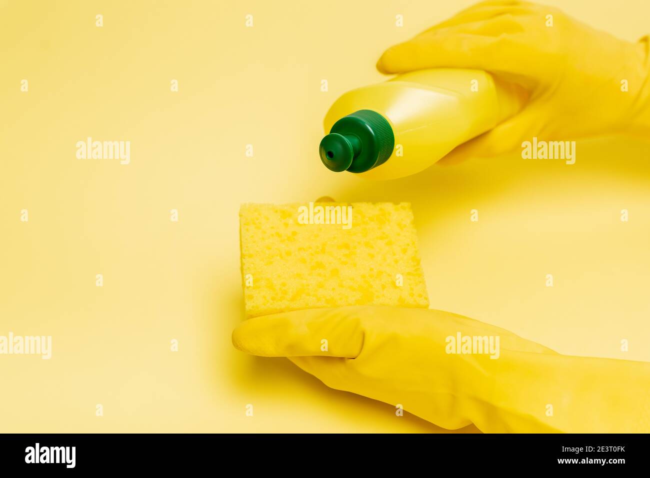 Cropped view of hands in rubber gloves pouring dishwashing liquid on ...
