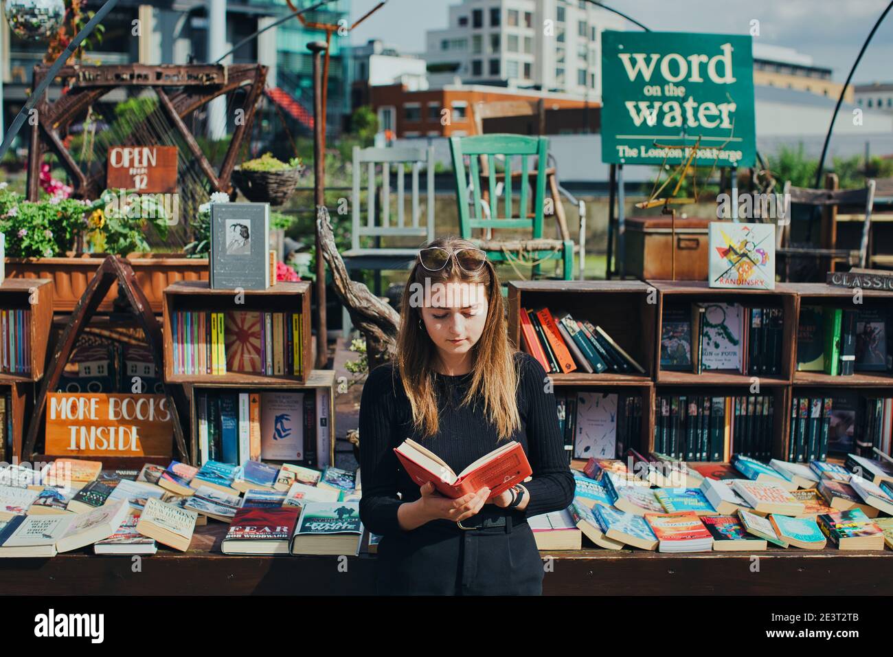 GREAT BRITAN / London / Bookstores / Woman is reading a book in fron of  Word On The Water  London’s Canalboat Bookstore . Stock Photo