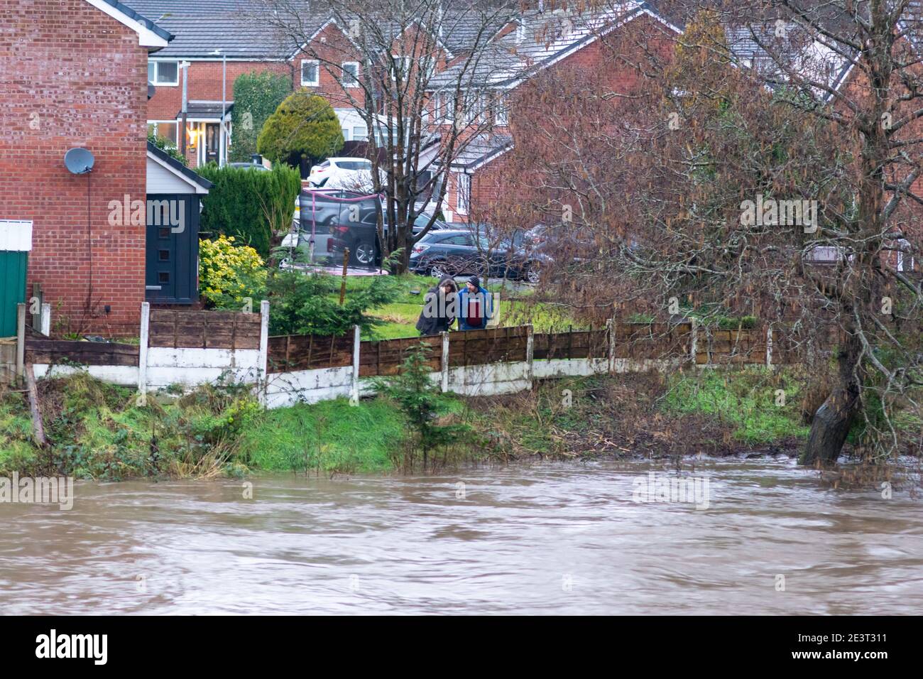 Prestolee, Bolton, England, UK. 20th Jan 2021. Consistent rainfall from Storm Christoph over the last 24 hours has led to the level of the River Irwell rising significantly. A couple at a property in Riverside drive, one of the most flood prone areas of the village, looks out anxiously from their garden onto the raging river. A flood warning has now been issued for the River Irwell at Prestolee and Ringley bridges. The village of Prestolee experienced flooding in 2015 and 2020 when the Irwell burst its banks. Credit: Callum Fraser/Alamy Live News Stock Photo