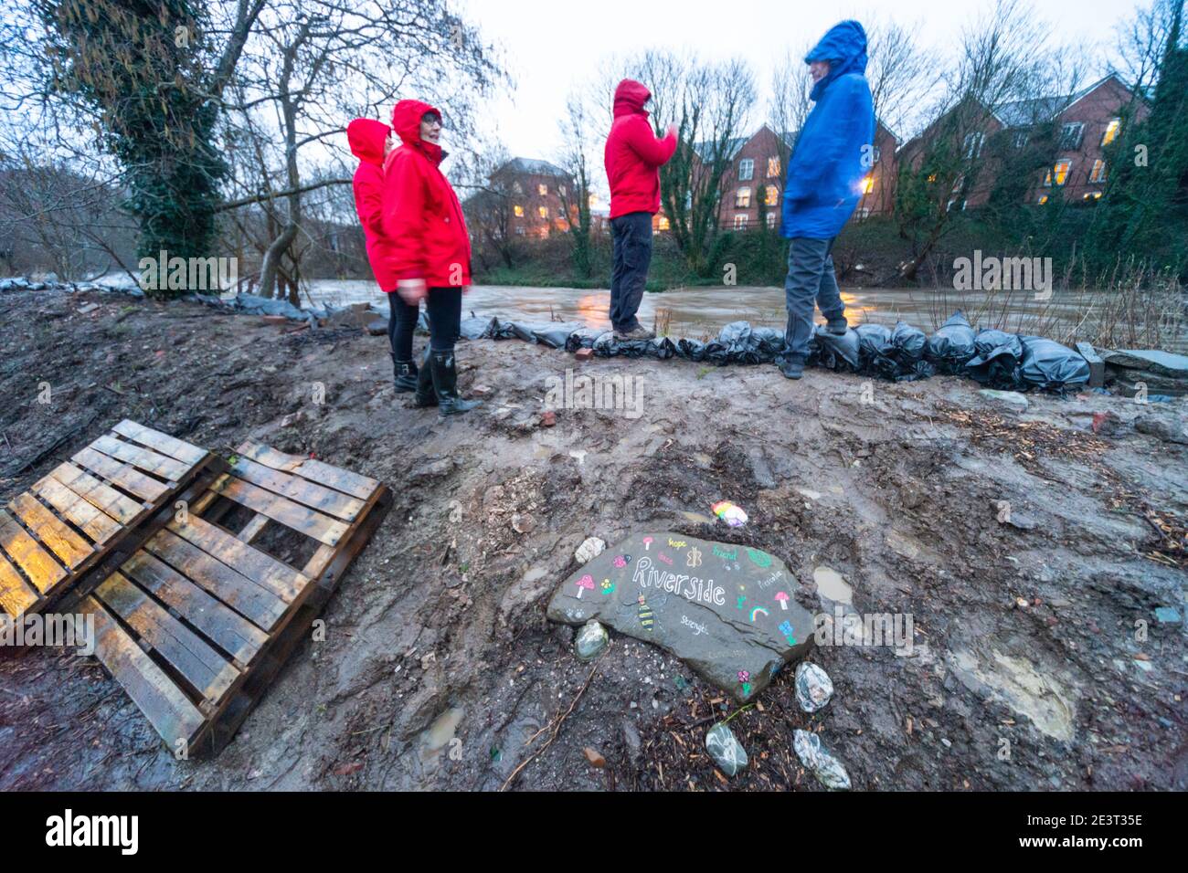 Prestolee, Bolton, England, UK. 20th Jan 2021. Consistent rainfall from Storm Christoph over the last 24 hours has led to the level of the River Irwell rising significantly. Residents stand next to stacked sandbags on the river banks at Riverside drive, one of the most flood prone areas of the village. A flood warning has now been issued for the River Irwell at Prestolee and Ringley bridges. The village of Prestolee experienced flooding in 2015 and 2020 when the Irwell burst its banks. Credit: Callum Fraser/Alamy Live News Stock Photo