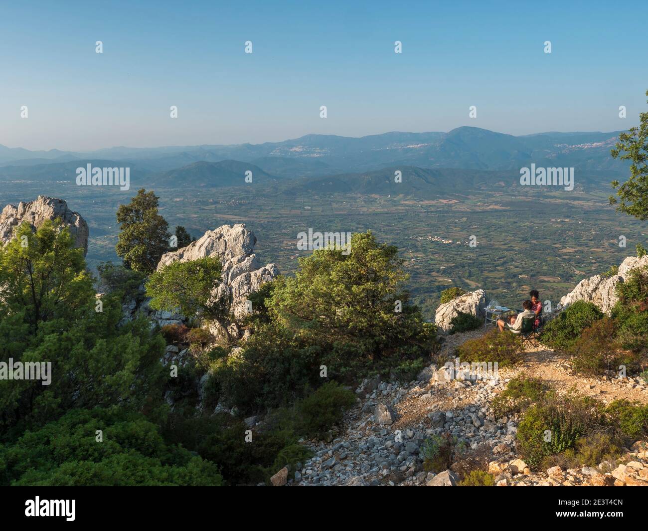 Baunei, Sardinia, Italy, September 17, 2020: Young happy couple having breakfast at Baunei viewpoint with green landscape of trees, limestone rocks Stock Photo