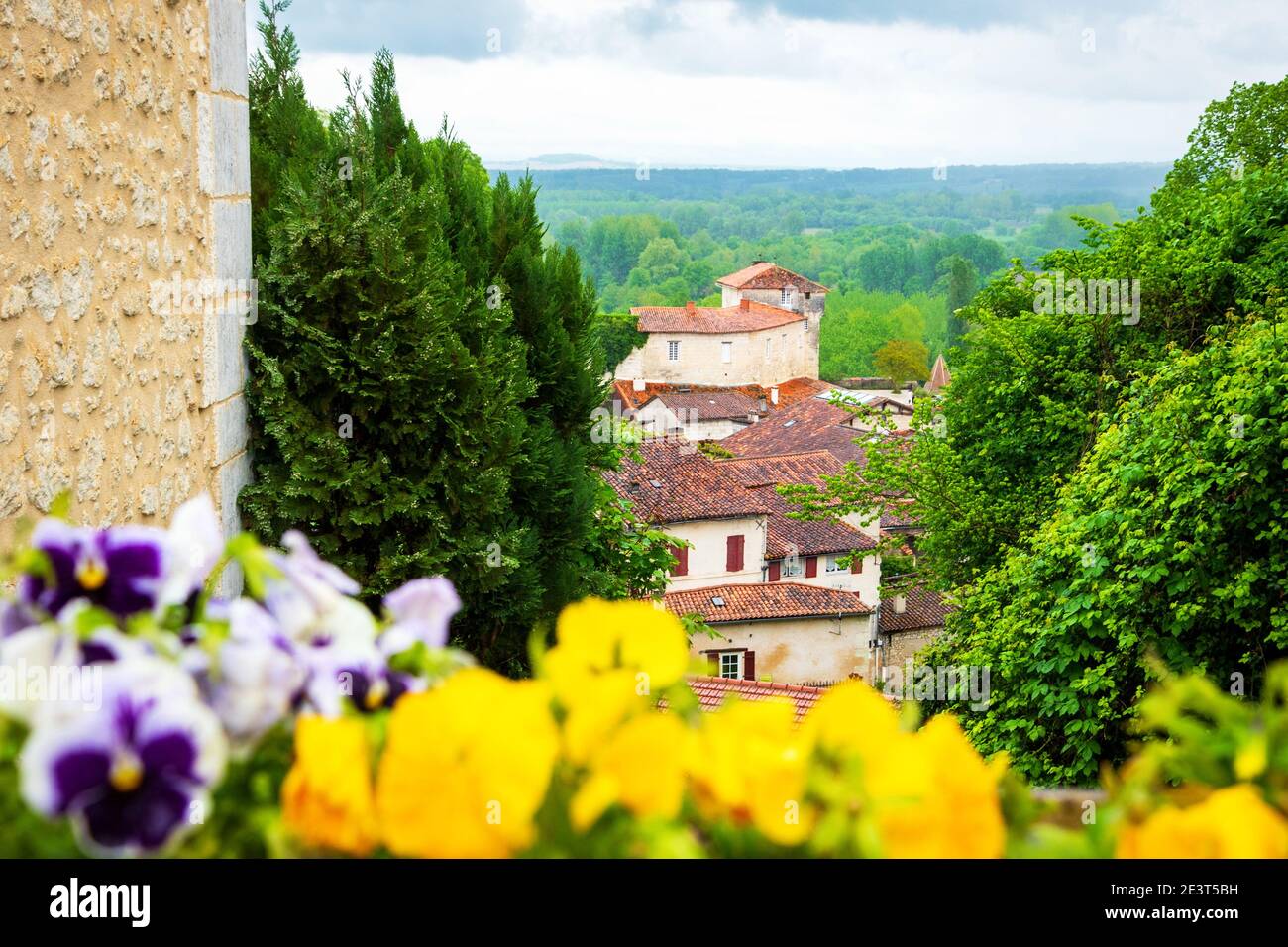 Aubeterre sur Dronne (France). Listed as 'One of the most beautiful villages in France' since 1993. Blurry pansy flowers at foreground. Stock Photo