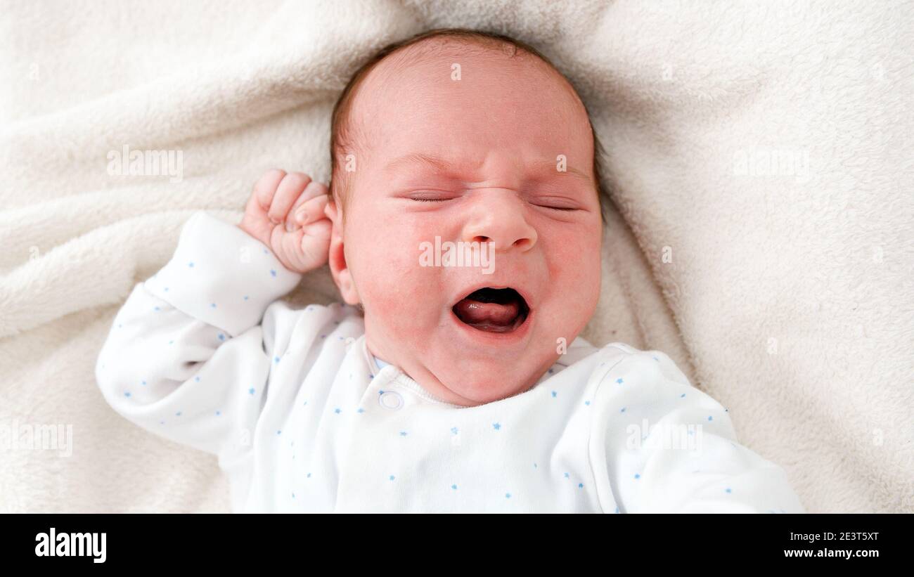Top view closeup shot of newborn baby boy crying beacuse of feeling