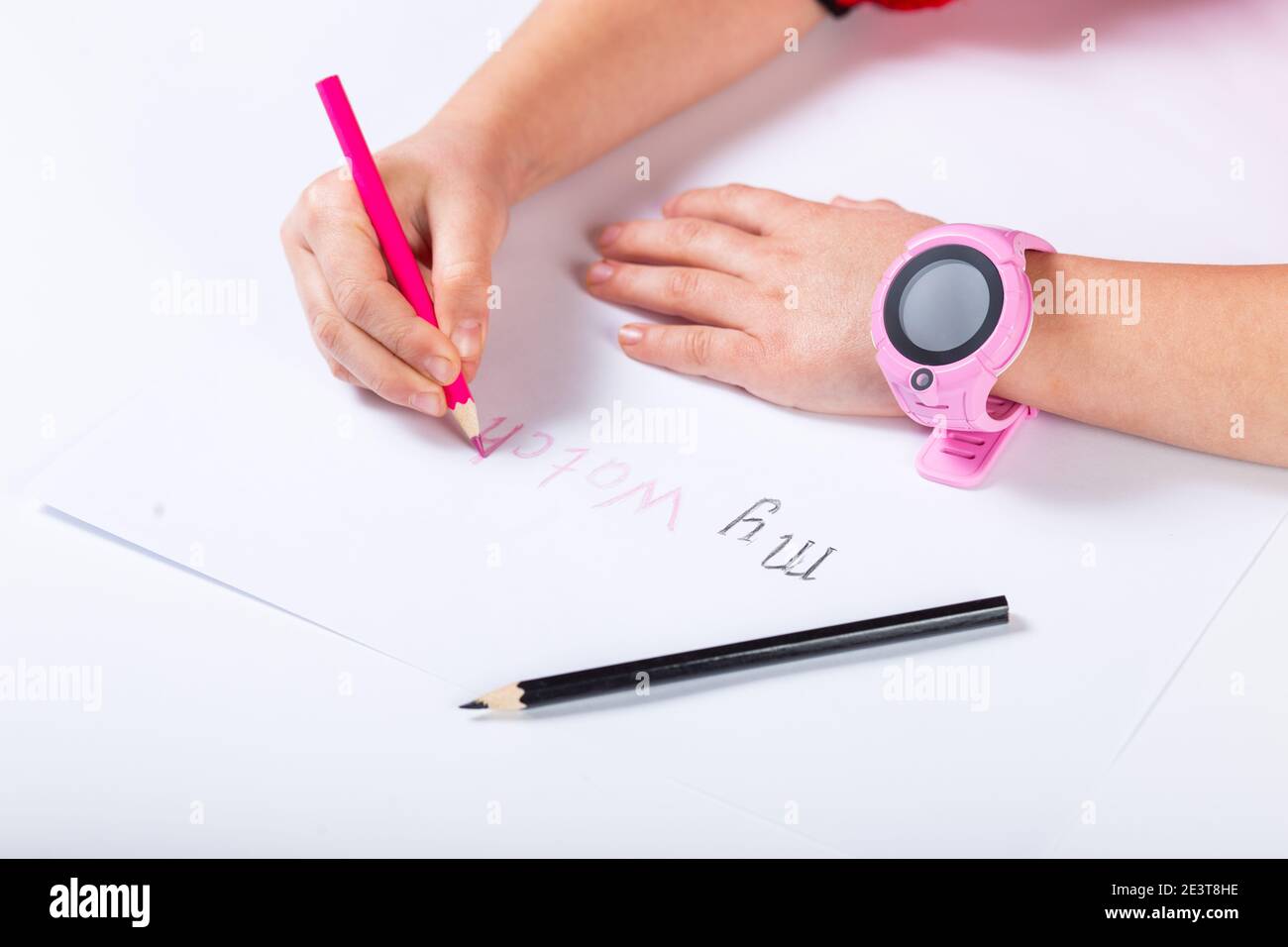 Child draws with pencils words my wath and on hand pink smart watch. Stock Photo