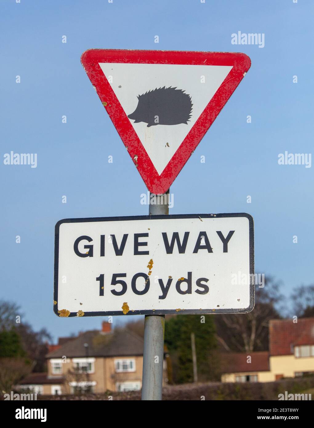 Red triangle give way warning sign marked with a black hedgehog sticker Stock Photo