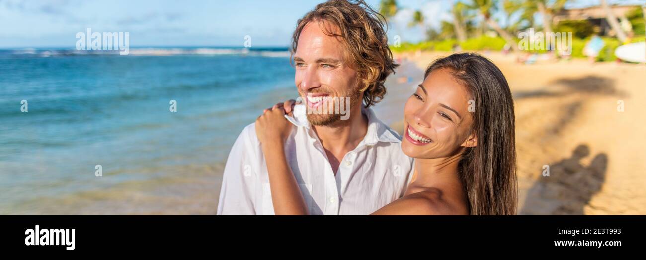 Healthy lifestyle vacation couple banner relaxing on beach honeymoon travel. Interracial young people in love at sunset. Panorama with copy space Stock Photo