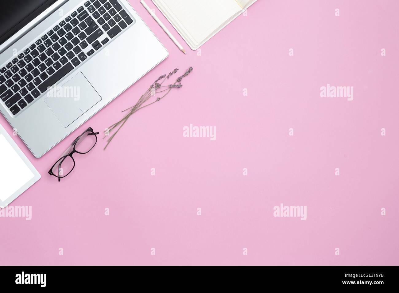 Stylish work feminine business desk with laptop and modern office attributes. Top view. Copy space. Flat space. Pink background. Stock Photo