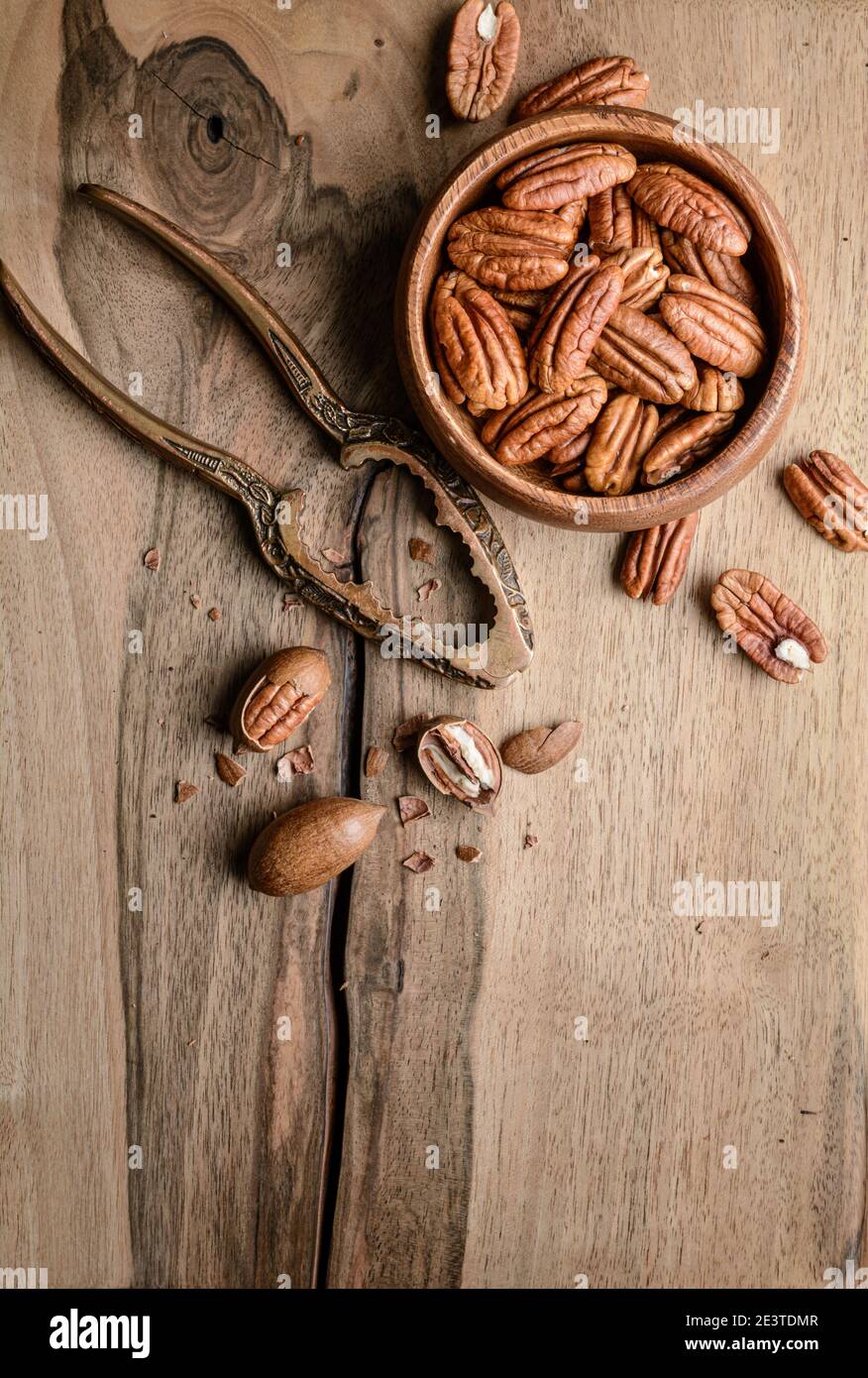 Healthy snack rich in vitamins and minerals, fresh shelled pecans in a bowl on wooden background with copy space Stock Photo