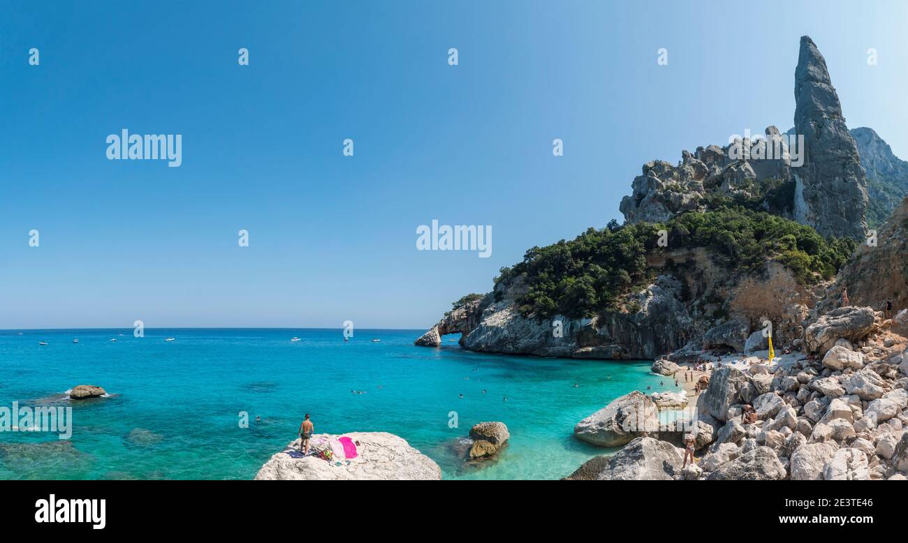 Gulf of Orosei, Sardinia, Italy, September 17, 2020: Panoramic view of Cala Goloritze beach with tourist people, limestone rock pillar Aguglia Stock Photo