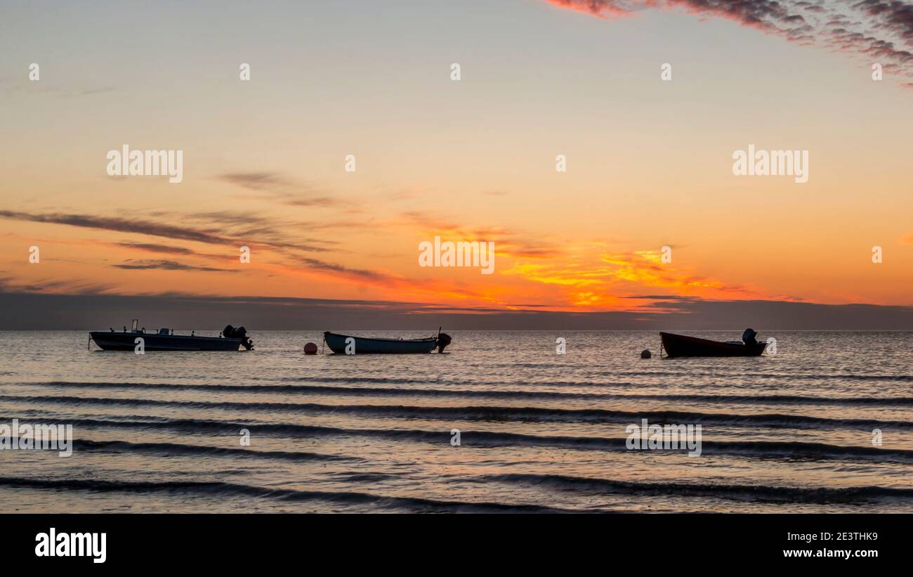 Beautiful sunset. pink, purple, golden, orange, blue colors over the sea. sky full of many colors. Boats in the water. Stock Photo