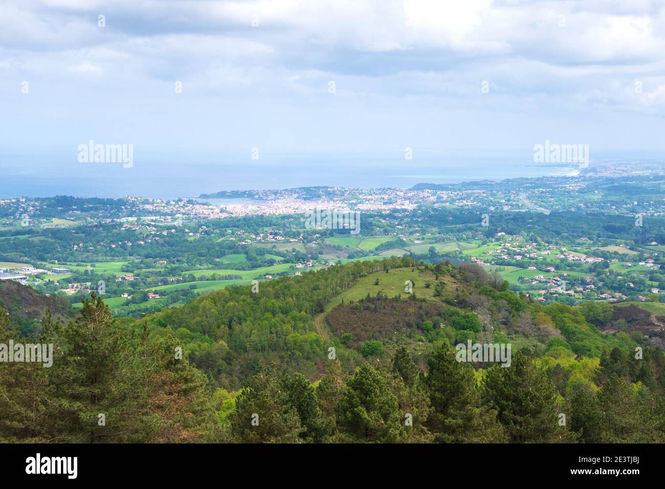 View from mountain of coastline  at Basque country on border between France and Spain in cloudy day. Burnt trees after fire on the hills. Stock Photo